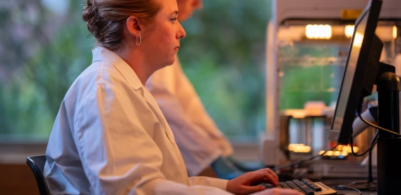 Technologist working at laboratory bench on a computer